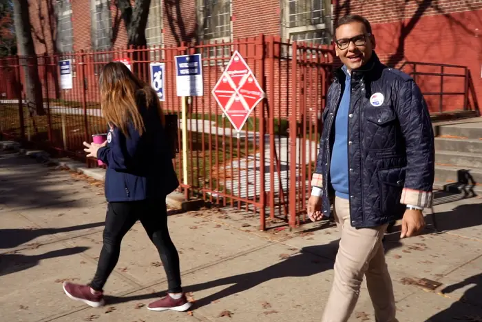 Rep.-elect George Santos waving as he walks out of a polling site